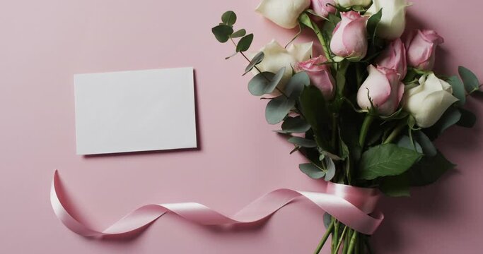 Video of bunch of white and pink roses with envelope and copy space on pink background