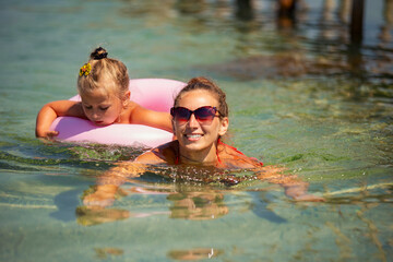 mother and daughter swim in the sea near the shore