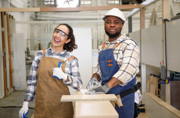 Portrait of a team of professional carpenters, men and women smiling happily in the design of furniture handicrafts in the factory.