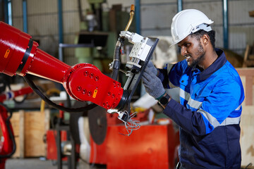 African engineer or worker checking and fixing machine in robot factory