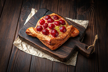 Lush puffs with cream and cherries and black currants on brown boards.  Berry cake. Bakery products. Fresh bakery.