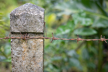 Cement fence posts and barbed wire, close-up