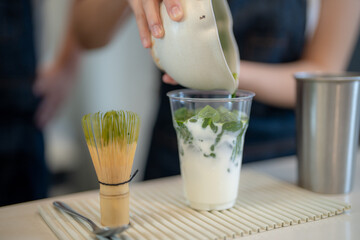 Barista workers are tasting green tea matcha drinks at the counter pantry of cafe. Man and women...