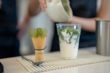 Barista workers are tasting green tea matcha drinks at the counter pantry of cafe. Man and women...