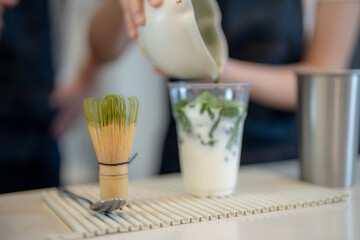 Barista workers are tasting green tea matcha drinks at the counter pantry of cafe. Man and women...