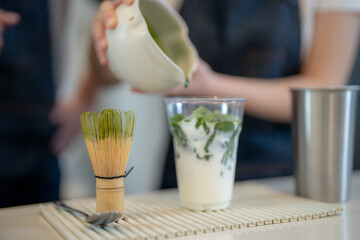 Barista workers are tasting green tea matcha drinks at the counter pantry of cafe. Man and women...