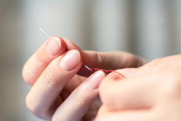 Woman holding in hand a stitching needles with the waxed thread close up. Leather craft concept.