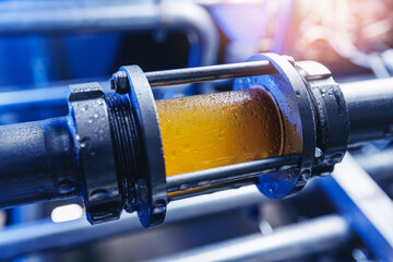 Brewing equipment for quality control, sight glass full of golden beer on stainless steel pipe....