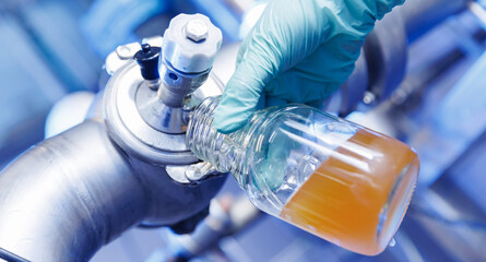 Laboratory assistant inspecting production beer, analysis drink in pipes stainless steel brewing...