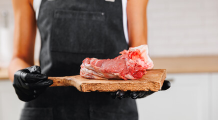Butcher woman prepare fresh meat pork entrecote steak on wooden board, top view on dark background