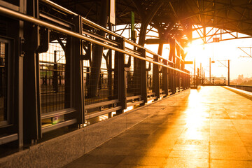 Rail and walkway at train platform in sunset