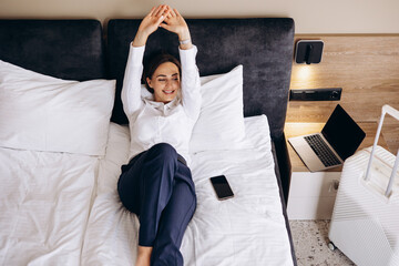 Business woman lying on a bed in a hotel room
