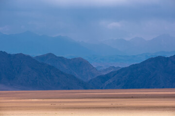 Rocky mountains over the desert, landscape in style of minimalism. Kazakhstan Almaty region, empty reservoir Bartogay due to drought.