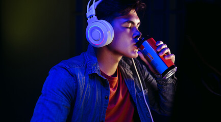 Computer gamer drinking an energy drink and taking a break from gaming at night