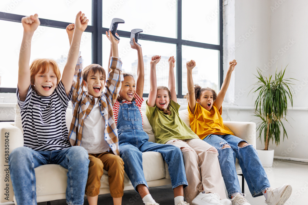 Wall mural group of joyful teenage friends with joysticks enthusiastically playing game console .