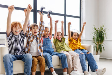 Group of joyful teenage friends with joysticks enthusiastically playing game console  .