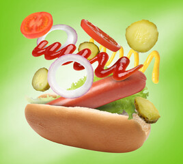 Hot dog ingredients in air on green gradient background