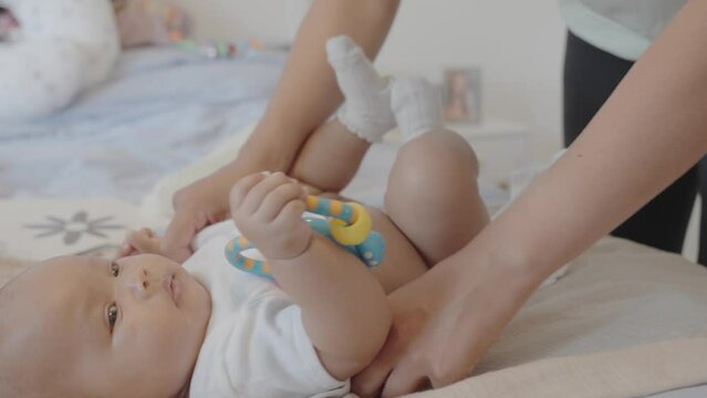 Woman changing baby daughters diaper in bedroom