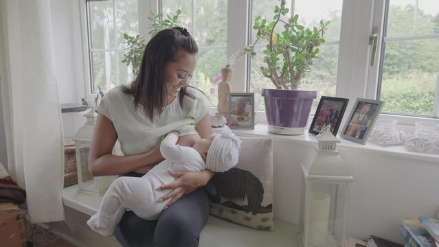 Woman breastfeeding baby girl at home