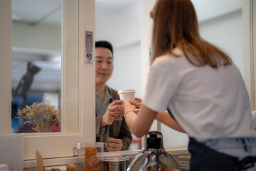 The Barista woman worker is serving a cup of coffee to customer at the counter pantry of the cafe....