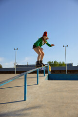 Teenager girl in roller skates riding on handrail practicing extreme tricks