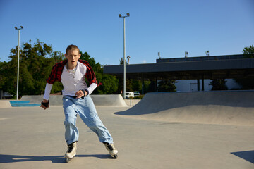 Obraz premium Trendy fashioned teenage guy rollerblading at urban skating park