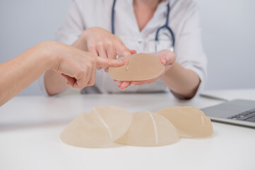 Caucasian woman and plastic surgeon touching and choosing breast implants. 