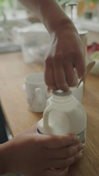 Close-up of woman pouring milk into mugs with coffee
