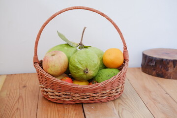  Basket of apples, oranges and guava on a wooden table, stock photo