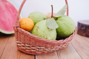 Basket of apples, oranges, guava and watermelon on a wooden table, stock photo
