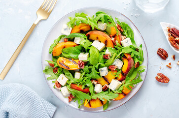 Grilled Peach Salad with Blue Cheese, Pecans and Arugula on Bright Light Blue Background