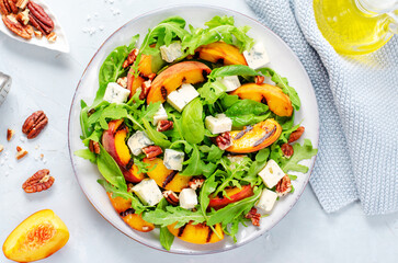 Grilled Peach Salad with Blue Cheese, Pecans and Arugula on Bright Light Blue Background