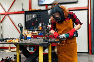 A self-taught girl grinds in the workshop, uses a visor and gloves for protection