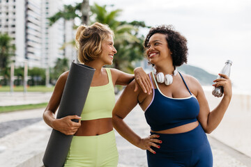 Two friends enjoying a beach workout with yoga mat and water bottle