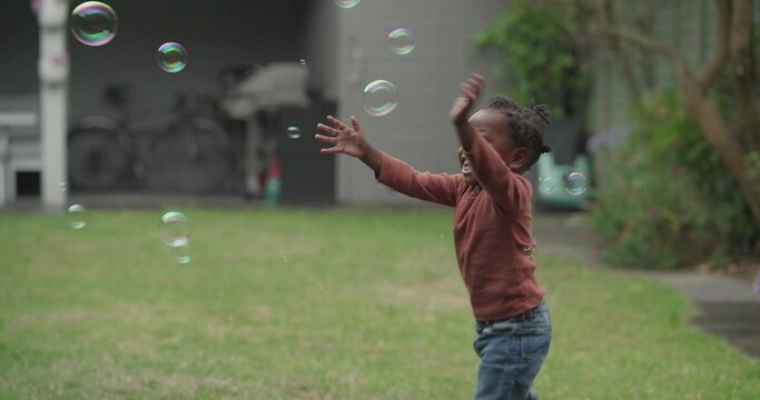 Girl playing with soap bubbles in garden