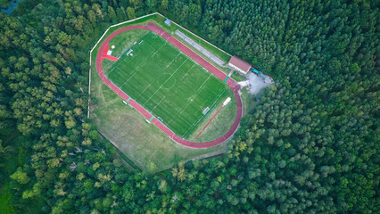 Drone top down view of town football field in summer deciduous forest. Calm cloudy day from tall...