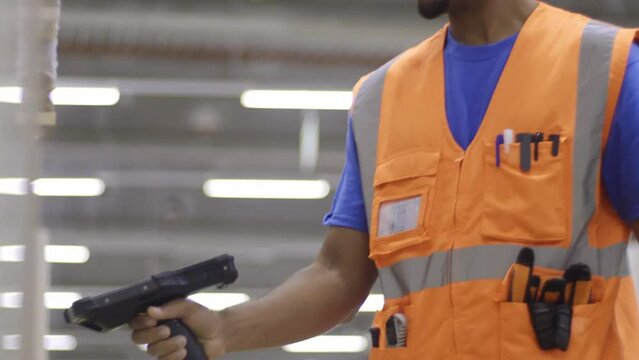 Warehouse worker using wireless barcode scanner while checking merchandise in stock. Storehouse african american man employee scanning goods with handheld reader