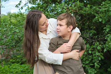 A mother and son share a joyous moment in a lush park, embodying the essence of authentic family bonds