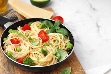 Delicious pasta primavera in frying pan and ingredients on white table, closeup