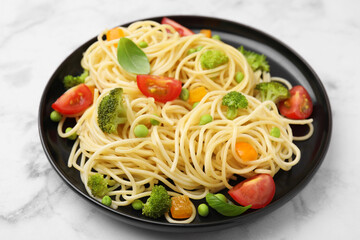 Plate of delicious pasta primavera on white marble table, closeup
