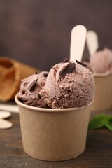 Paper cups with tasty chocolate ice cream on wooden table, closeup