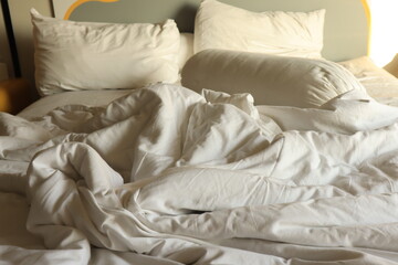 Fototapeta na wymiar messy hotel bed. White pillow. White roll. white blanket.