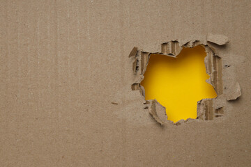 A hole in kraft cardboard on a yellow background.