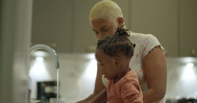 Mother and daughter washing dishes in kitchen