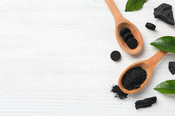 Activated charcoal tablets with wooden spoon and leaves