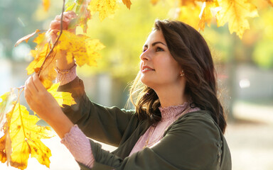 Young woman looks at colorful autumn leaves