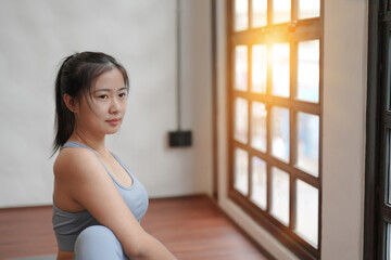 Portrait of young beautiful Asian woman warm up exercise work at fitness at home. Healthy and wellness lifestyle concept. Asian woman exercising in yoga fitness studio