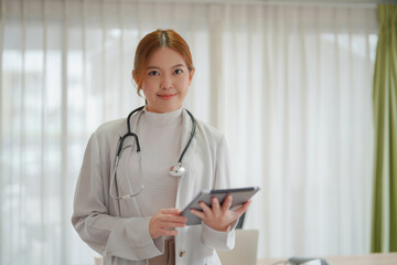 Asian woman doctor wearing white with tablet.