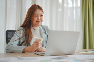 Beautiful Asian business woman working on laptop and her paperwork in the office.