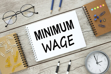 Minimum Wage gray wooden background table clock bright paper clips on a notebook layout. text on...